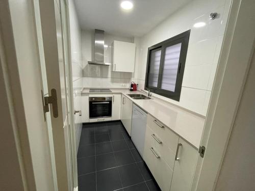 una pequeña cocina con armarios blancos y una ventana en CasaMar, en Barbate