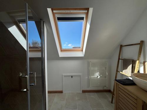 La salle de bains est pourvue d'une douche en verre et d'une lucarne. dans l'établissement Saint Ho Mer Maison lumineuse vue mer 8 pers 4 chambres 2 sdb 2 WC étage rénové en 2025 belle terrasse grand jardin clos parking 8 mn à pied petite plage grand jardin près de Port en Bessin, Bayeux et plage Omaha beach, à Sainte-Honorine-des-Pertes