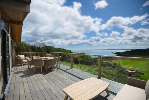 una terrazza con tavolo, sedie e vista sull'oceano di Muir Lodge a Gatehouse of Fleet