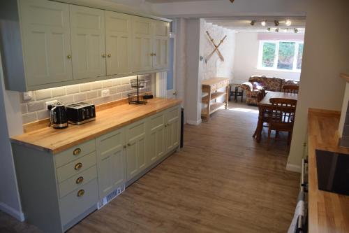 Una cocina con gabinetes blancos y una encimera de madera. en Munro Cottage, en Rockcliffe