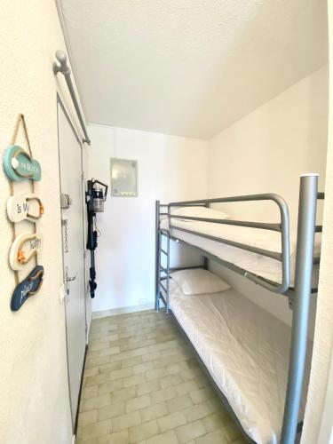 Cette chambre comprend 2 lits superposés et une porte. dans l'établissement PORT CAMARGUE - CHARMANT STUDIO CLIMATISE POUR 4 PERSONNES AVEC TERRASSE + PARKING, au Grau-du-Roi