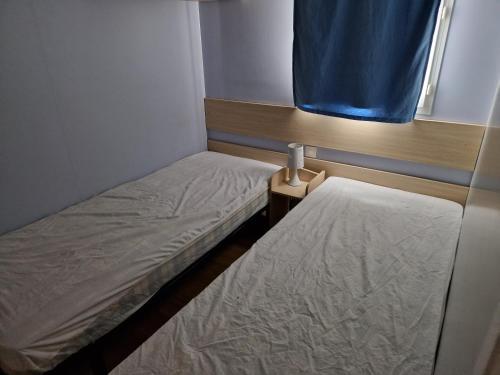 a small room with two beds and a window at Mobil-home Andernos Les Bains 4pers in Andernos-les-Bains