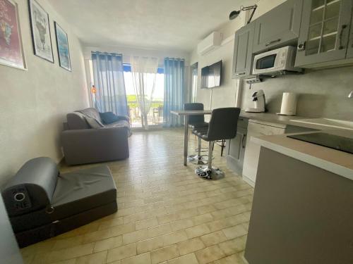 une cuisine et un salon avec une table et des chaises dans l'établissement PORT CAMARGUE - CHARMANT STUDIO CLIMATISE POUR 4 PERSONNES AVEC TERRASSE + PARKING, au Grau-du-Roi