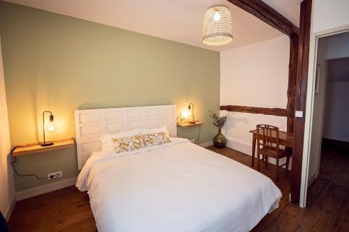 a bedroom with a large white bed and a chair at Mercerie de Denise in Le Bourg-Dun