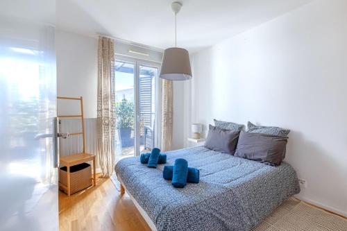 a bedroom with a bed with blue pillows on it at Beautiful 2 bedroom in Palaiseau Ideal for professionals in Palaiseau