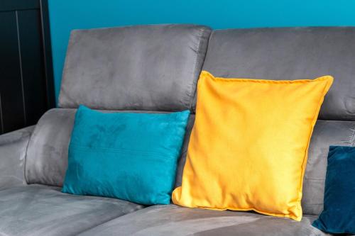 a gray couch with two blue and yellow pillows at Beautiful 2 bedroom in Palaiseau Ideal for professionals in Palaiseau