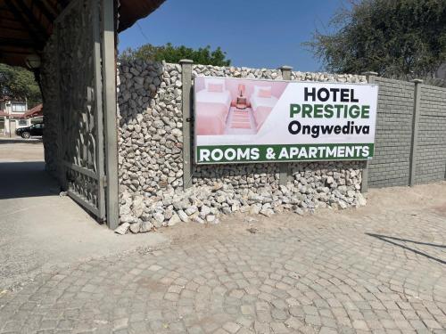 a stone wall with a sign for rooms and apartments at Hotel Prestige Ongwediva in Ongwediva