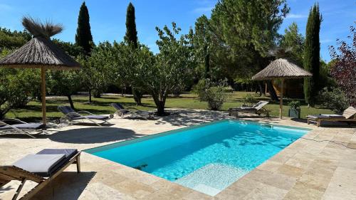 une piscine avec chaises et parasols dans une cour dans l'établissement La maison à couleur - Mas provençal avec piscine, à Châteaurenard