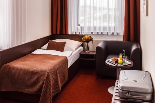 a hotel room with a bed and a chair at Interhotel Zlín in Zlín