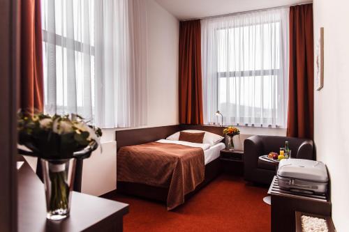a hotel room with a bed and a chair at Interhotel Zlín in Zlín