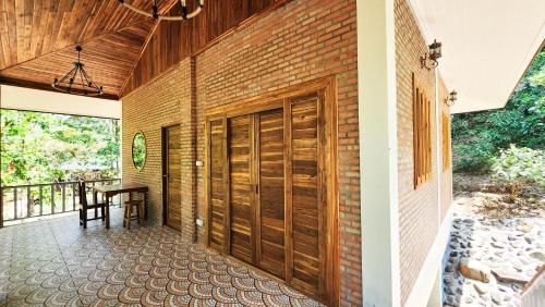 a brick wall with wooden doors on a patio at Baan Bhuwann Forest Chalet in Koh Phangan
