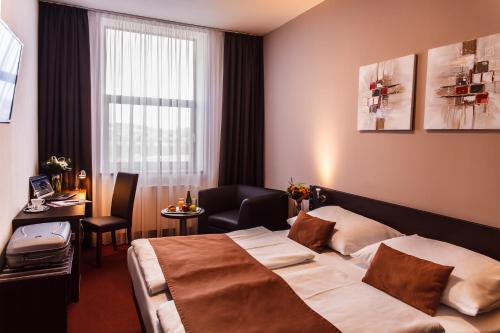 Interhotel Zlín في زلين: غرفة فندقية بسرير وطاولة ونافذة