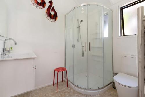 a white bathroom with a shower and a stool at Deluxe Seaview Chalet 6 by Palm Beach Chalets in Palm Beach