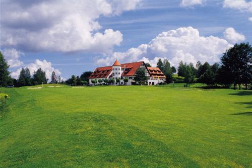 a large green field with a large house at Golfhotel Bodensee by Michael Ritter in Weißensberg
