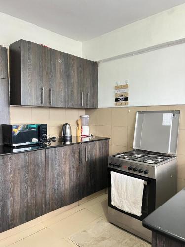 a kitchen with wooden cabinets and a stove top oven at comfortplace 2 bedrooms in town behind National bank in Kericho