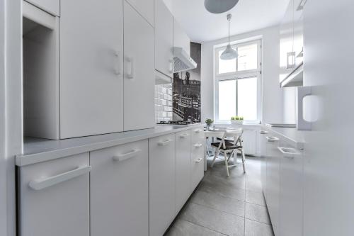 a white kitchen with white cabinets and a table at Mieszkanie przy deptaku Sopot in Sopot