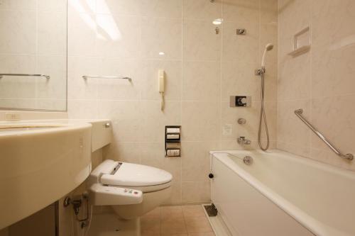 a bathroom with a toilet and a tub and a sink at Hotel Keihan Universal Tower in Osaka