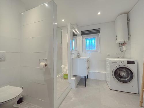 une salle de bain blanche avec une machine à laver et un lavabo dans l'établissement Vue mer et parking privé, T2 avec accès plage, à Fréjus