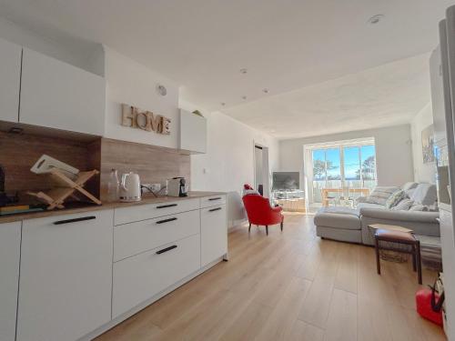une cuisine avec des placards blancs et un salon avec un canapé dans l'établissement Vue mer et parking privé, T2 avec accès plage, à Fréjus