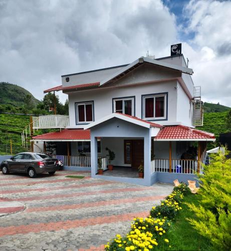 a white house with a car parked in a parking lot at Cloud & Mist Inn-Stay with Mountain Views in Kotagiri, Near Ooty in Kotagiri