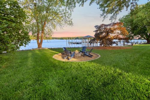 a fire pit in the grass next to a lake at Southern Sunrise Covered Dock & Optional Boat Rental in Mooresville