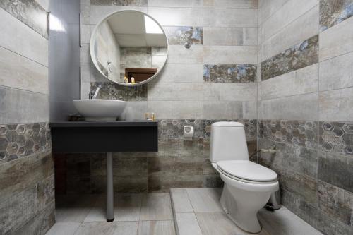 a bathroom with a toilet and a sink and a mirror at Family Hotel Central in Shumen