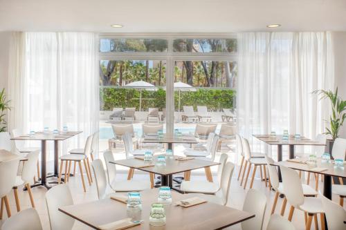 a restaurant with tables and chairs and a large window at Sol Palmanova Mallorca in Palmanova