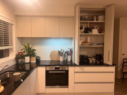 a kitchen with white cabinets and a black counter top at Best on the Block minimum four nights in Auckland