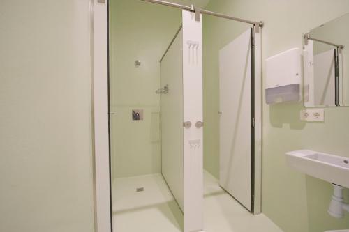 a bathroom with a shower, sink, and mirror at A Room In The City Hostel in San Sebastián