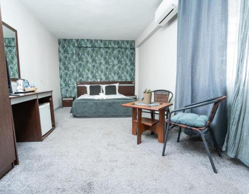 a bedroom with a bed and a table and a chair at Family Hotel Central in Shumen
