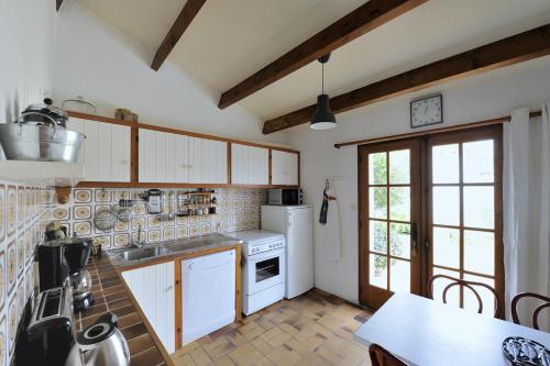 - une cuisine avec des appareils électroménagers blancs et une table dans l'établissement La Maison de Flo, à Noirmoutier-en-l'lle