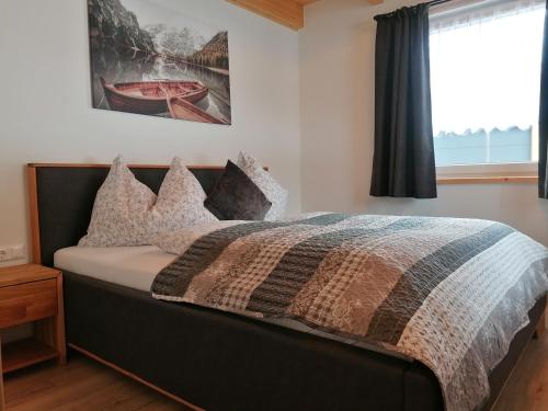 a bed with a comforter and pillows in a bedroom at BergAufe Chalets Mallnitz in Mallnitz