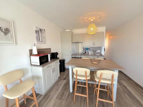 une cuisine avec une table et des chaises dans une pièce dans l'établissement Le murmure des vagues - appartement vue mer - idéal télétravail, à Wimereux