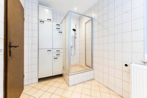 a bathroom with a shower and white tiled walls at Monteurwohnung Dresden-Klotzsche I in Dresden