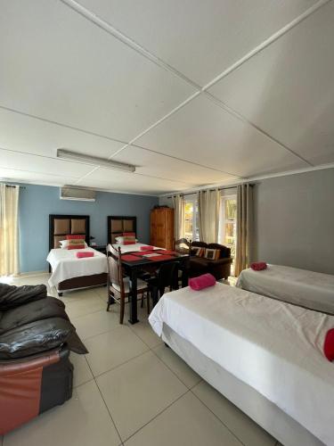 a room with two beds and a table in it at Zinzanathi Guest house in Ladysmith