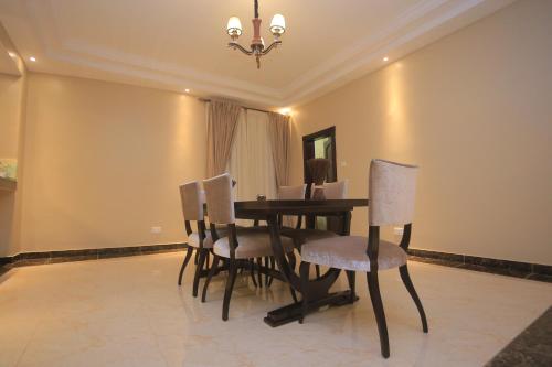 a dining room table with chairs and a chandelier at Ssanga courts Apt in Kampala