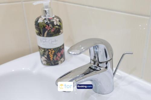 a bathroom sink with a faucet and a bottle of soap at 2 Bedroom Apartment By The One Retreats Short Lets & Serviced Accommodation Horley Close To Gatwick Airport in Horley