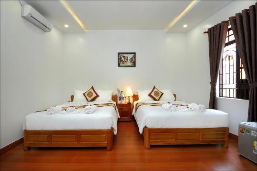 1 dormitorio con 2 camas con sábanas blancas y ventana en Blue Lake Homestay, en Hoi An