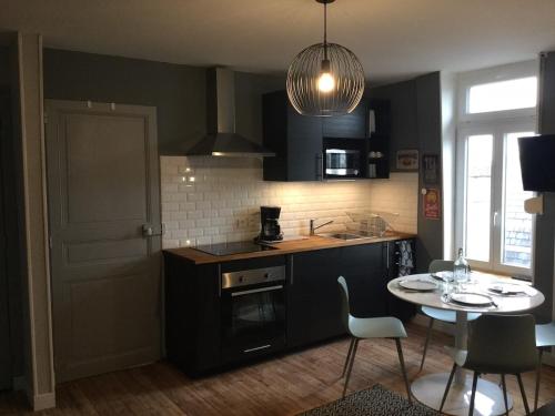 une cuisine avec des armoires noires et une table avec des chaises dans l'établissement Résidence Molière M3, à Soissons