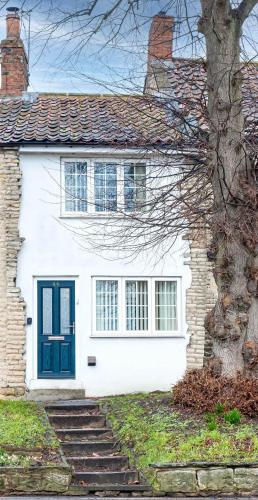 a white house with a blue door and stairs at Cosy one bedroom cottage in Pickering in Pickering