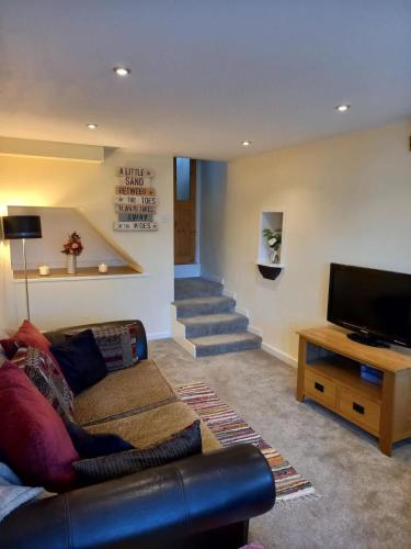 a living room with a couch and a flat screen tv at Cosy one bedroom cottage in Pickering in Pickering