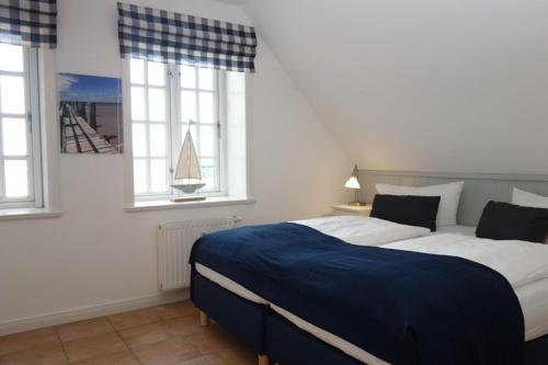 a bedroom with a large bed and two windows at Hüs Dikstian- Wohnung 5 in Alkersum