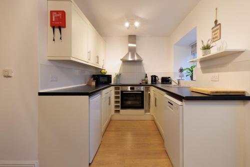 a kitchen with white cabinets and black counter tops at Heather Cottage - a beautiful cosy cottage for couples in Snainton