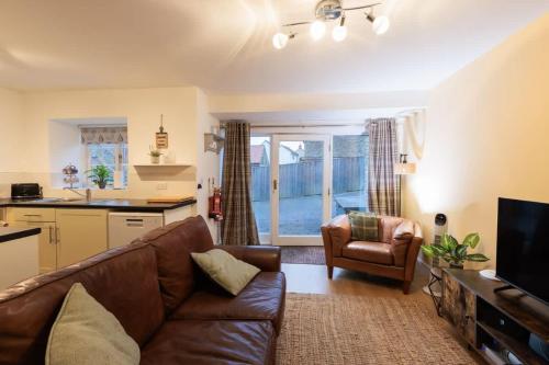 a living room with a brown couch and a kitchen at Heather Cottage - a beautiful cosy cottage for couples in Snainton