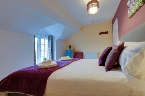 a bedroom with a large white bed with purple pillows at Lavender Cottage - a beautiful quirky family cottage in Snainton