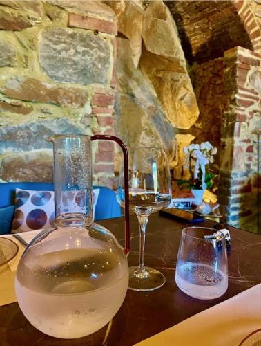 a table with two glasses and a vase of wine at Morelliana4Rooms in Scansano