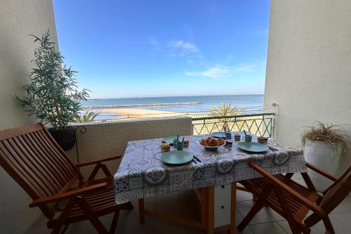 une table et des chaises sur un balcon avec vue sur la plage dans l'établissement La Croix du Sud 4 - Appartement en duplex Vue Mer 1ère ligne avec terrasse, au Grau-du-Roi