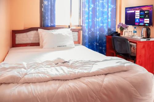 a bedroom with a bed with a desk and a television at Durban Hotel in Dar es Salaam