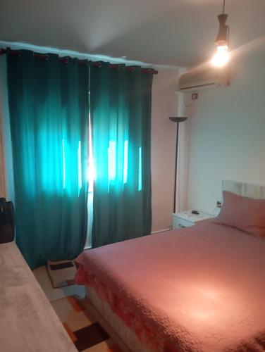 Un dormitorio con una cama y cortinas verdes. en VLORE 1+1, en Vlorë