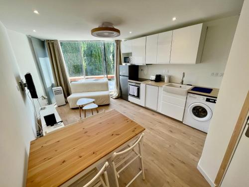 une cuisine avec des armoires blanches et une table dans une pièce dans l'établissement PGH N20 - Centre-Ville, à La Grande Motte